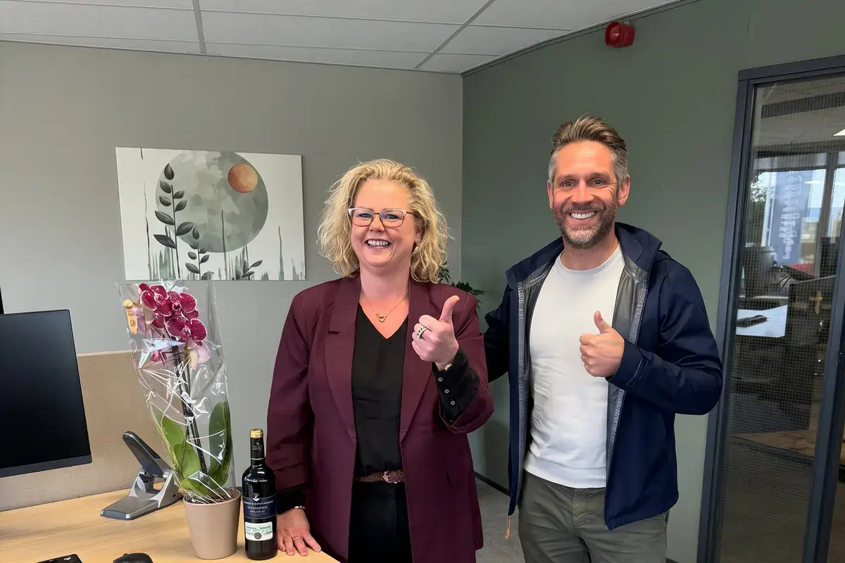 Dave en een collega geven een duim omhoog in een modern kantoor
